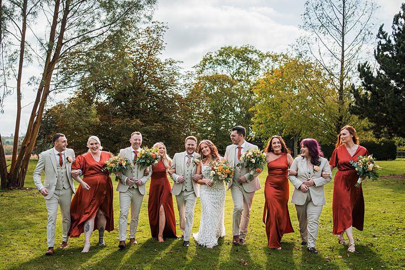 Wedding party walking in garden, smiling and joyous.