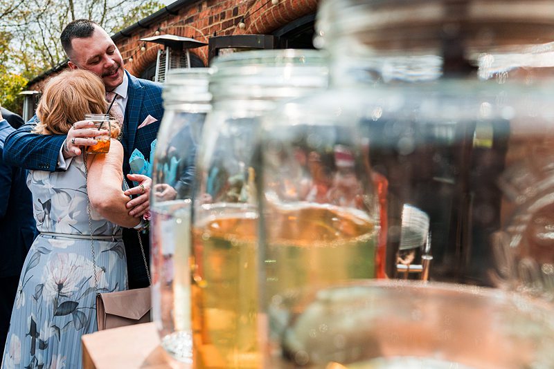 People hugging at outdoor event with drink jars.