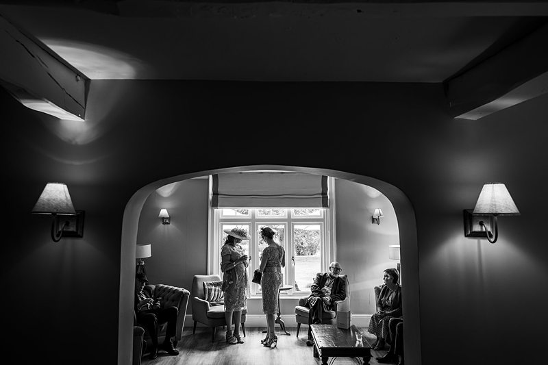 People conversing in a living room, black and white.