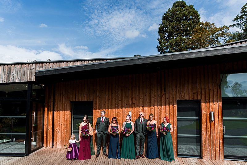 Wedding party outside modern wooden building.