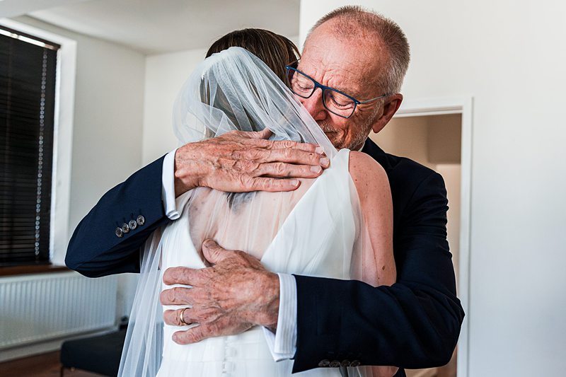 Bride hugging father in emotional wedding moment.