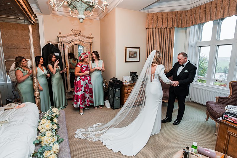 Bride and groom with bridesmaids in elegant room.