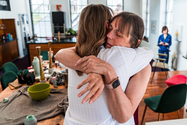 Two people hugging warmly in a cosy room.