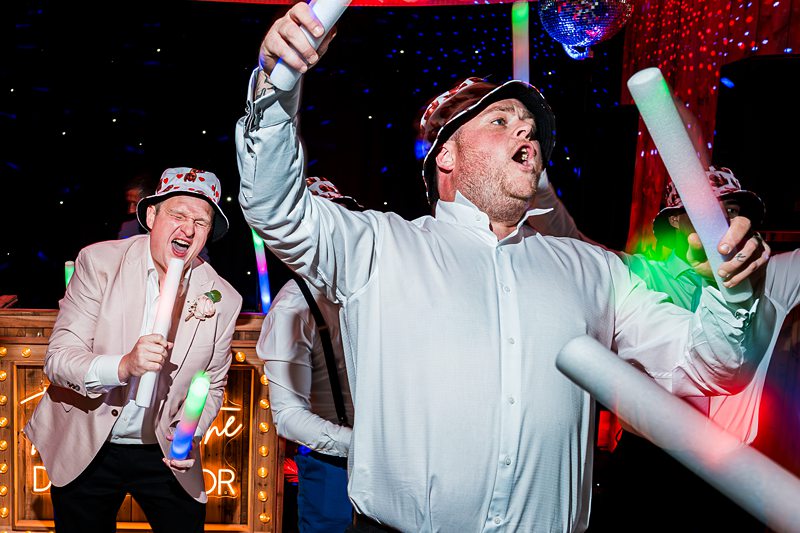 Men enjoying a lively party with foam sticks.