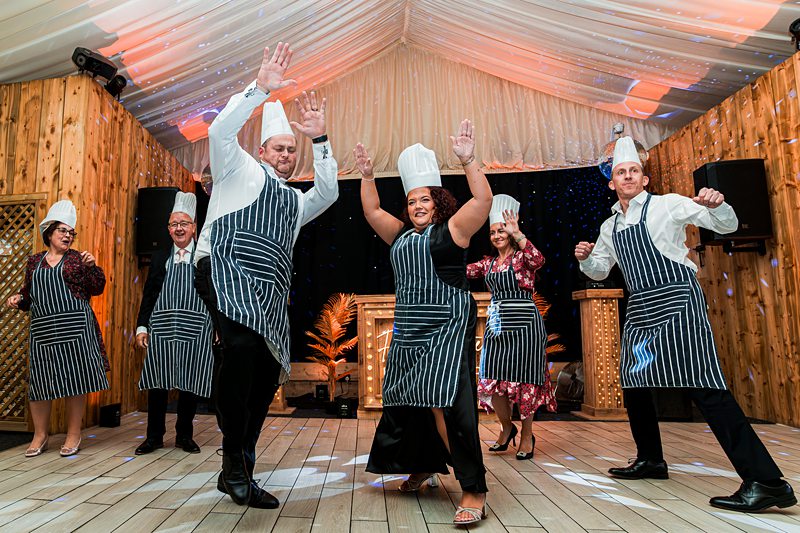 Group in chef hats dancing joyfully at event.