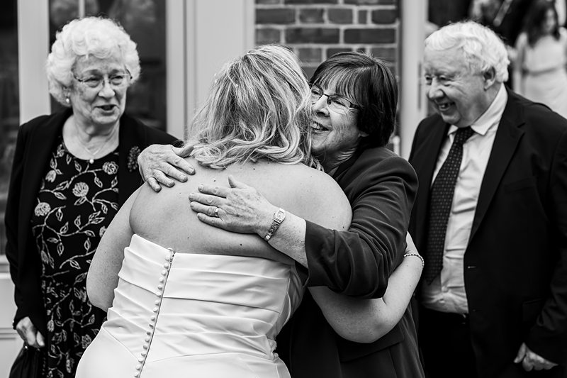 Bride hugs guests at wedding celebration.
