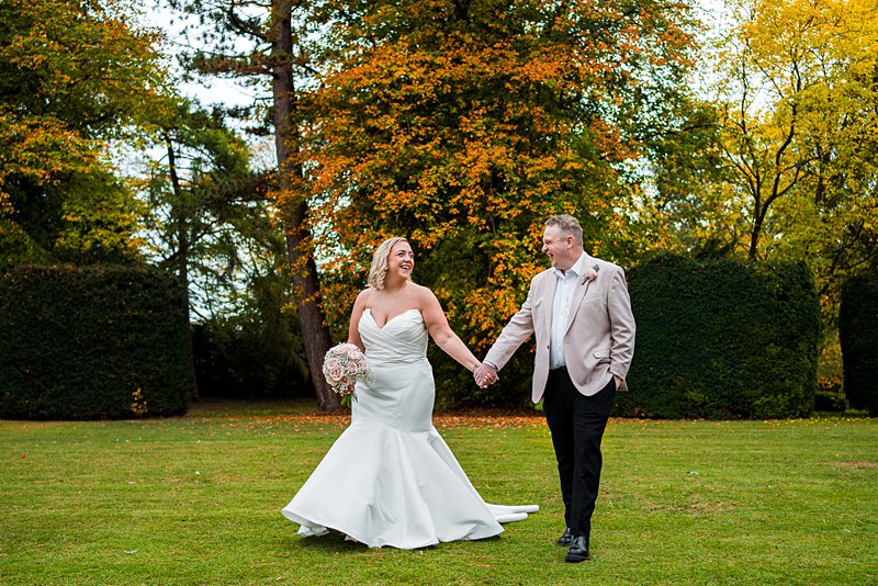 Bride and groom walking in autumn garden