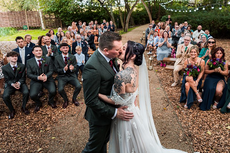Bride and groom kiss in outdoor wedding ceremony.