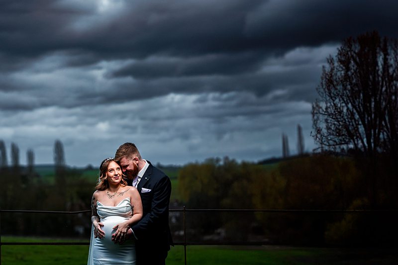 Couple embraces under dramatic cloudy sky.