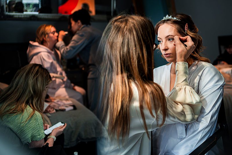 Bridal party getting makeup done before wedding ceremony.