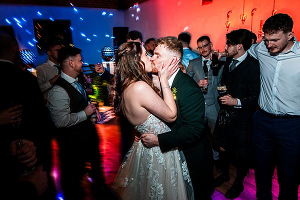 Couple kissing on a vibrant dance floor.