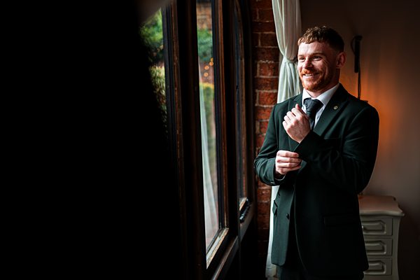 Man in suit smiling by a window