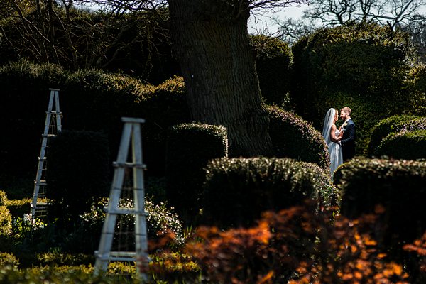 Bride and groom embrace in garden