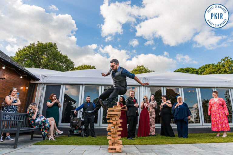 Man balancing on giant outdoor Jenga blocks at event.