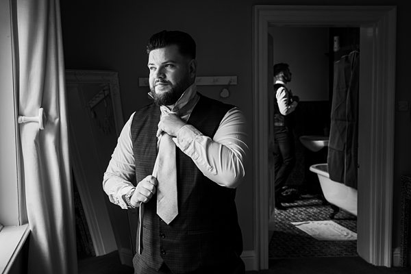 Man adjusting tie in front of mirror