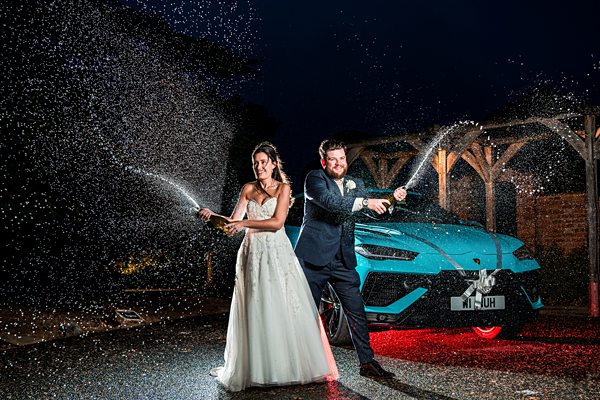 Bride and groom spraying champagne at night
